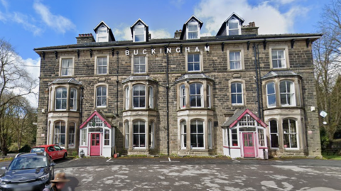 Three-storey building with red doors and the word 'Buckingham' in letters at the top of the building