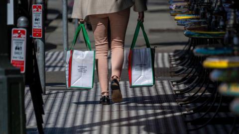 A shopper carries shopping bags in the North Beach neighborhood in San Francisco, California, US, on Tuesday, March 11, 2025. 