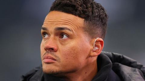 Jermaine Jenas wearing a coat and looking impassively off camera