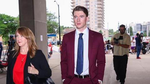 Carter Hart arrives at the London Courthouse, in London, Ontario, Canada on July 24, 2025. He is wearing a maroon suit and blue tie.
