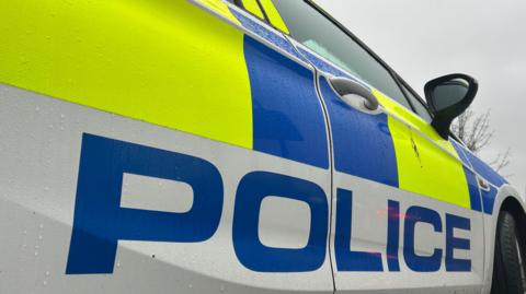 The outside of a Devon and Cornwall Police car taken from a low angle showing the full righthand side of the car.