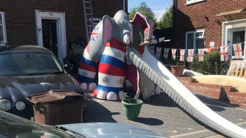 A multi-coloured elephant slide in a driveway of someone's house.