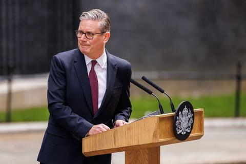 Sir Keir Starmer - a man wearing a dark suit and red tie - stands at a lectern with the government crest on it outside No 10 Downing Street