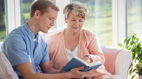 A woman and a younger man look at a book together