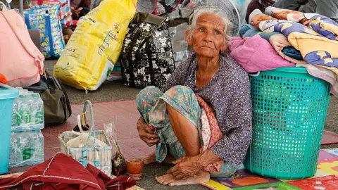 An old woman sitting at a temporary shelter
