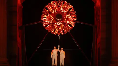 Spectators pose for photos ahead of the Opening Ceremony of the Milano Cortina 2026 Winter Olympic Games at the Giuseppe Meazza stadium in Milan, Italy