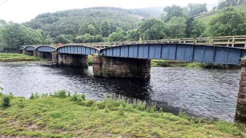 A viaduct in the Borders across water with rolling hills in the background