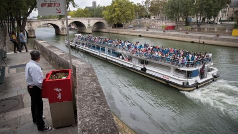 A man stands at a "uritrottoir" public urinal on August 13, 2018, on the Saint-Louis island in Paris