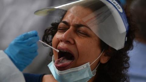 A healthcare worker collects a swab sample for the Covid-19 test, from a passenger arriving on an international flight at a facility inside the Chennai International Airport in Chennai, India, 01 August 2021.