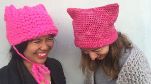 Pussyhat Project co-founders Krista Suh and Jayna Zweiman are seen laughing - wearing their hats