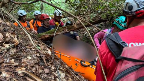 The hiker being carried out on a litter