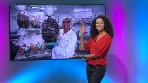 Nina in the studio with a picture of herself in the screen with a giant easter egg