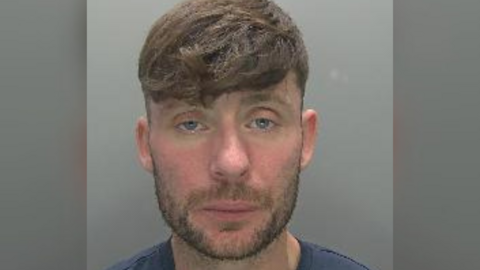 A custody image of Kevin Wall. He has brown hair and a short brown beard.