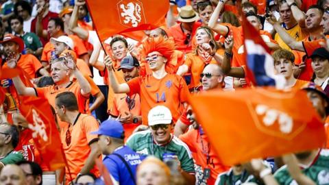 Dutch fans wearing orange and waving flags