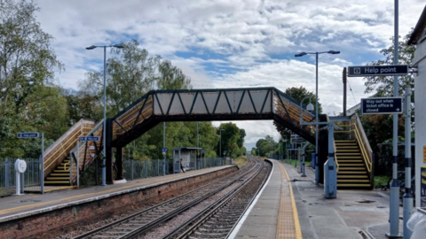 A general view picture of the current footbridge at Earley rail station in Berkshire, with two platforms either side of it, taken on a fine, sunny day.