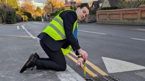 A councillor pictured with measuring tape