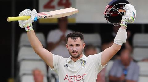 Ollie Robinson raises his bat after hitting a century for Durham against Essex