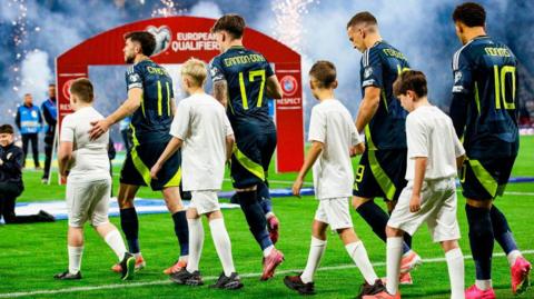 The Scotland squad walks out on to the pitch alongside mascots during a 2026 FIFA World Cup Qualifying match between Scotland and Greece at Hampden Park