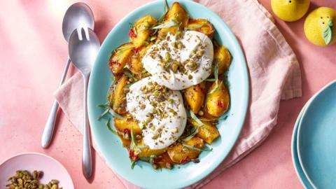 Nectarine and burrata salad on a blue plate.