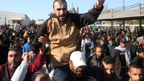 A man lifts his arm as he is surrounded by a crowd