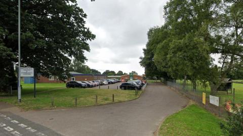 A road leading to the former Broadland Youth and Community Centre. The centre can be seen in the distance beyond a car park.   