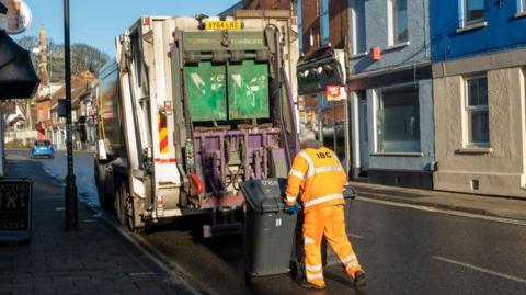 A council bin worker empties bins into a lorry in Ipswich, Suffolk