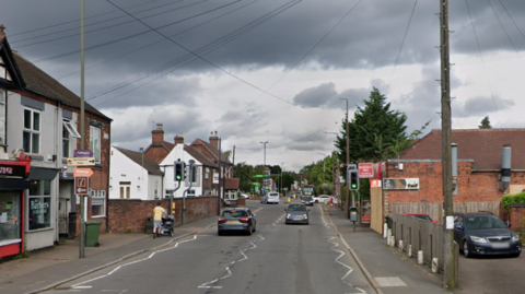 A long street through a town with cars on it