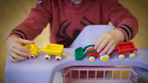 Stock image of a child - whose face cannot be scene - playing with toys.
