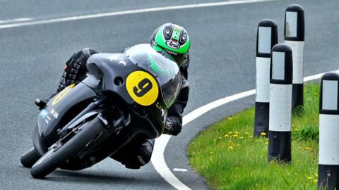 Mike Browne, wearing a green helmet, rides a black bike with the number nine on the front in a yellow plate
