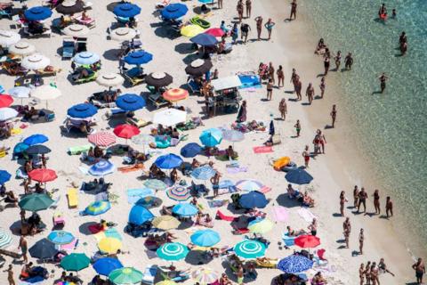 Beach umbrellas blanket sand real estate at the water's edge of Punta Molentis.