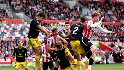 Manchester United defender Harry Maguire (second left) heads out of a packed penalty area at Brentford