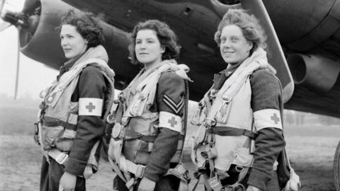 Black and white image of Leading Aircraftwoman Myra Roberts (left), Corporal Lydia Alford (middle) and Leading Aircraftwoman Edna Birbeck (right) in front of RAF plane in June 1944