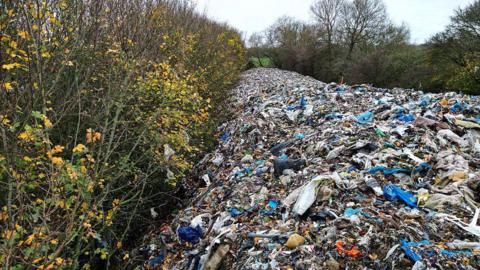 A view of a massive mound of illegally dumped rubbish has turned a field near Kidlington, Oxfordshire, into what locals call an "environmental disaster unfolding before everyone's eyes,"