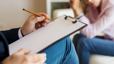 Psychologist interviewing sad woman during a counselling and therapy session.