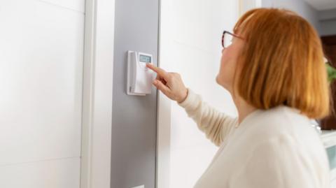 Woman adjusting thermostat