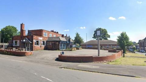 A Google Map photo of the Red Lion pub on Batley Road. The venue has a large car park and is located next to a busy road.