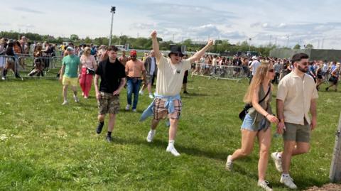 A man holds his hands up in an excited way as he enters the festival
