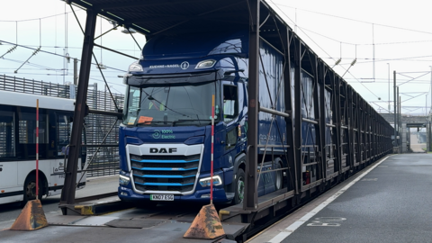 A blue HGV is parked on a freight train