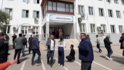 A grab of a video shows police, health workers and civilians outside a school were a shooting is reported to have taken place in southern Turkey