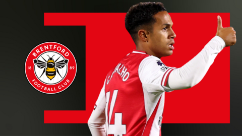 Fabio Carvalho, wearing Brentford's home shirt and with his thumb up, against a red and black background and next to the Brentford club crest.