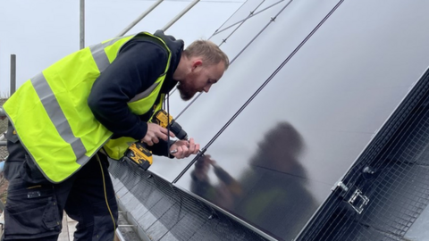 An installer working on an array of solar panels