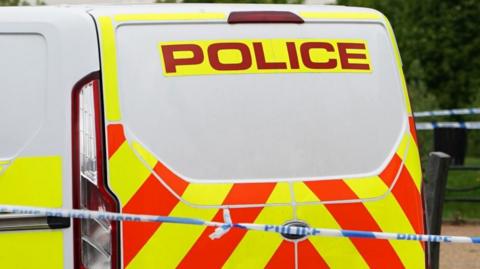 A stock image of a police van with police tape in front of it.