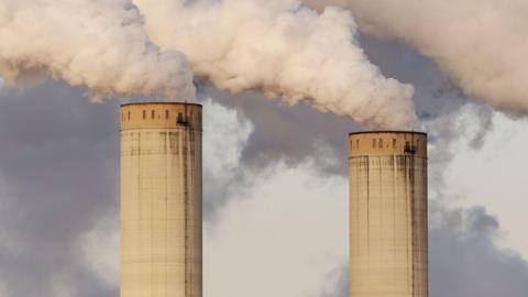 Two large chimneys with smoke coming out of them