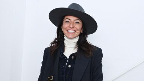 Davina McCall wearing a big hat and smiling.