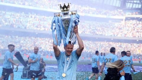 Manchester City players lift league cup on pitch