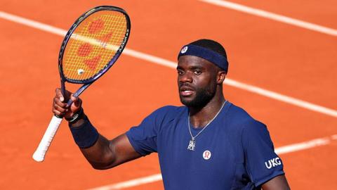 Frances Tiafoe raises his racquet at the French Open