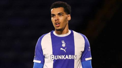 Jake Leake in a blue and white striped Oldham shirt