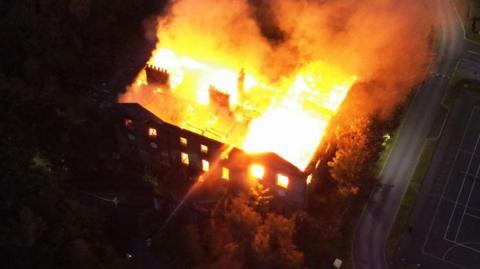 A manor house engulfed by flames