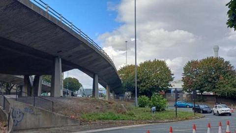 Several cars approaching the Park Lane roundabout. Above it stands the concrete Gateshead flyover.
