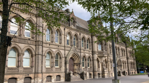 Middlesbrough Town Hall is a grand grey stone building with arched windows and a large wooden doors.